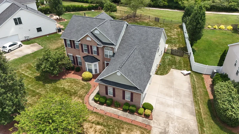 Drone view of a brick home with a completed gray shingle roof
