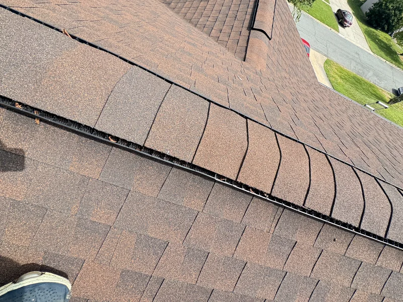 Close view of a shingle-covered ridge vent on a brown roof